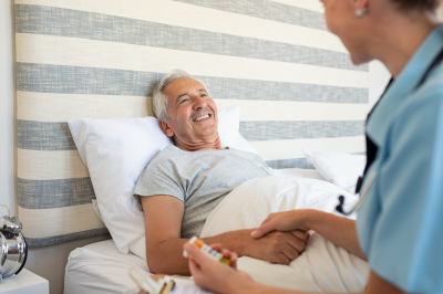 nurse and senior man holding hands